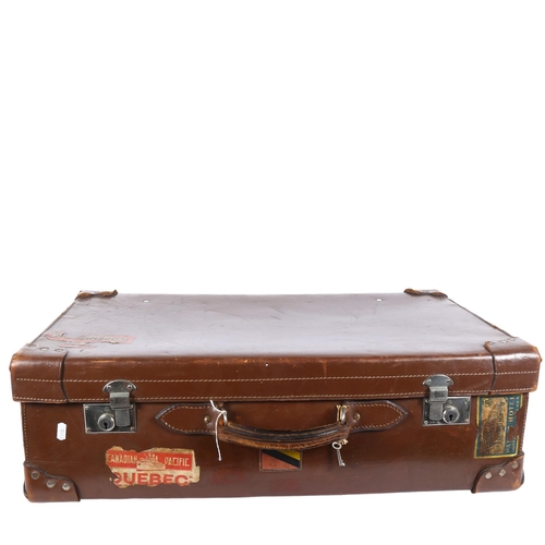 94 - A Vintage leather-covered cardboard suitcase, with several travel labels, the chrome plate locks imp... 