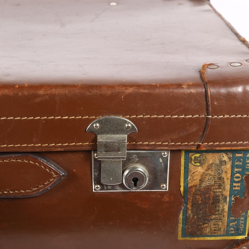 94 - A Vintage leather-covered cardboard suitcase, with several travel labels, the chrome plate locks imp... 