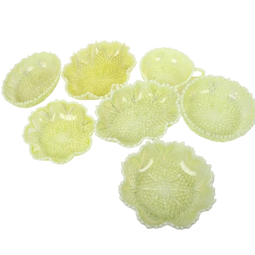 563 - A set of 7 moulded vaseline glass dishes, with shaped rims, largest 20cm across