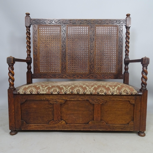 2697 - A 1920s oak hall settle with cane-panelled back, lifting seat and carved decoration, 106 x 108 x 48c... 