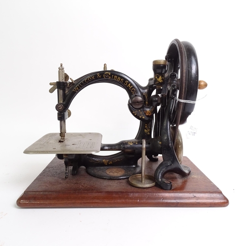 455 - Antique Willcox & Gibbs sewing machine with gilded decoration, on plinth, with original tin for acce... 