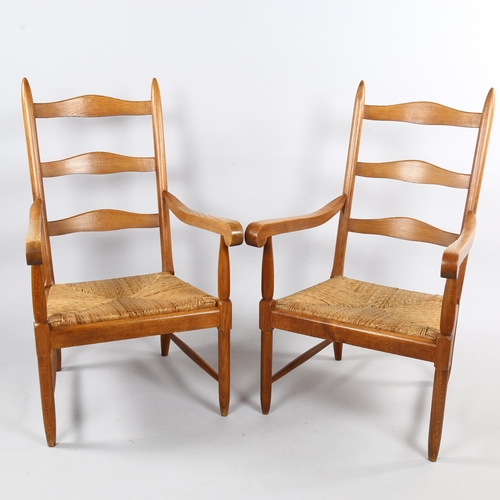 125 - A pair of mid-century ladderback lounge chairs, in oak with rush seats in the Cotswold School Arts a... 