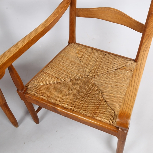 125 - A pair of mid-century ladderback lounge chairs, in oak with rush seats in the Cotswold School Arts a... 