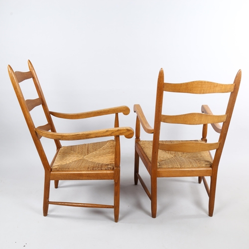 125 - A pair of mid-century ladderback lounge chairs, in oak with rush seats in the Cotswold School Arts a... 