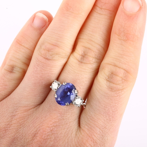 1159 - A platinum three stone tanzanite and diamond ring, set with oval mixed-cut tanzanite and modern roun... 