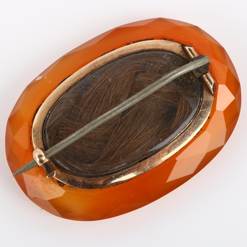 1161 - A Georgian faceted carnelian mourning brooch, with central double-sided plaited hair panel under con... 