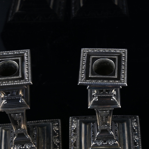 1709 - A pair of Victorian Neo-Classical style silver table candlesticks, square tapered form with relief e... 