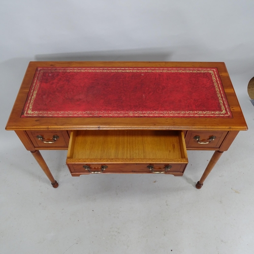 2224 - A reproduction yew-wood writing table with tooled and embossed red leather skiver and three fitted d... 