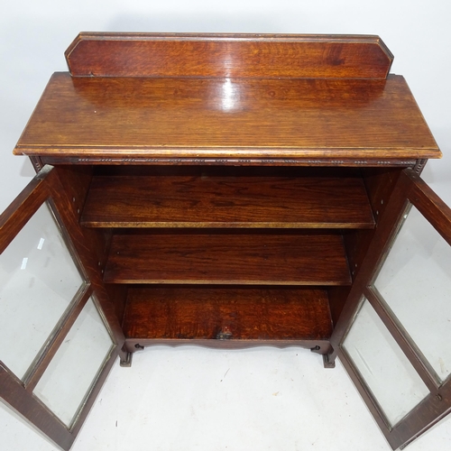 2273 - A 1930s oak bookcase with raised back and two glazed doors. 77cm x 104 cm x 27cm