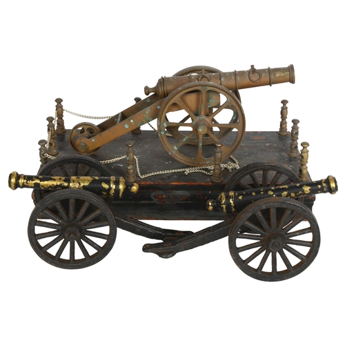 190 - A brass model cannon on wood base, length 31cm, and a pair of smaller painted brass model cannons