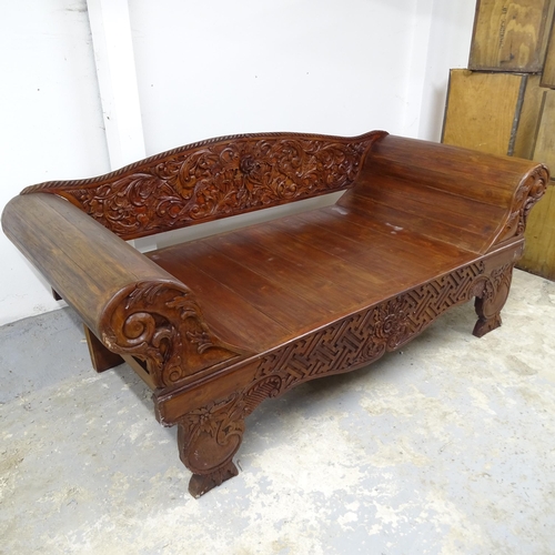 2553 - A contemporary Indian hardwood daybed with rollover arms and carved back. 230cm x 97cm x 99cm