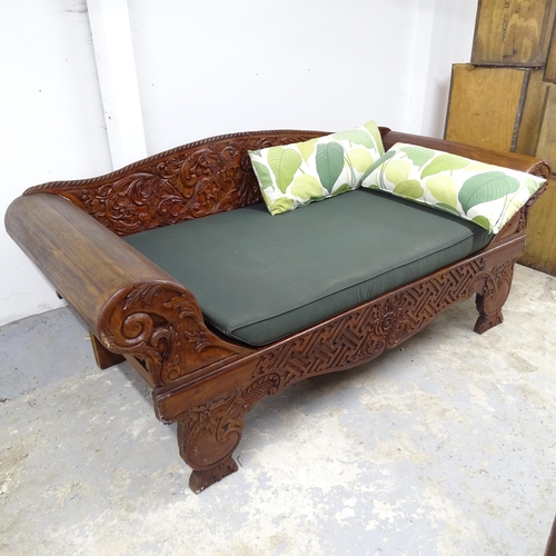 2553 - A contemporary Indian hardwood daybed with rollover arms and carved back. 230cm x 97cm x 99cm