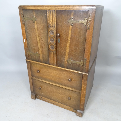 2578 - A 1930s oak tallboy with two carved panelled doors and two drawers under, label for Berick Furrnitur... 