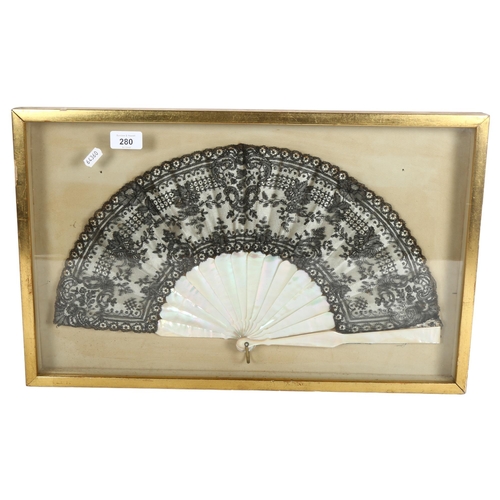 280 - A decorative Oriental style fan, lace panelled with mother-of-pearl spines, in a display case, lengt... 