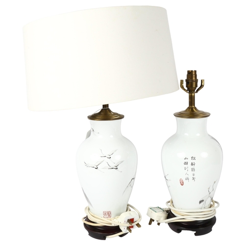 527 - A pair of Japanese porcelain table lamps, with design of mountains and cranes, with matching white s... 