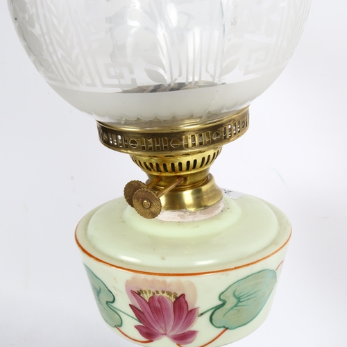 647 - A Victorian and brass oil lamp, with etched clear glass shade and milk glass painted font, on a terr... 