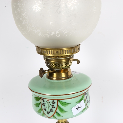 648 - A Victorian brass oil lamp, with a cranberry and clear glass etched shade and painted green glass fo... 