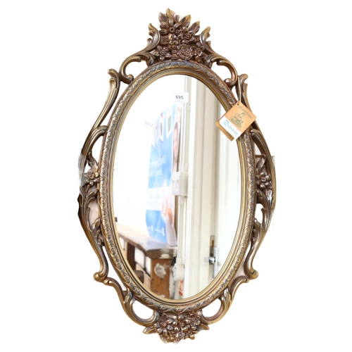 695 - A Syroco American composition-framed oval wall mirror, height 70cm