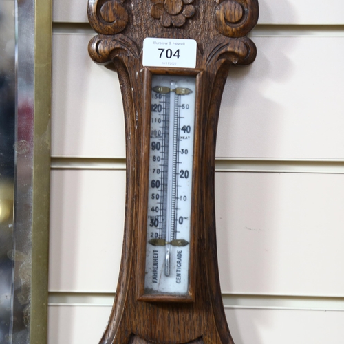 704 - A carved oak-cased aneroid barometer with thermometer, 64cm