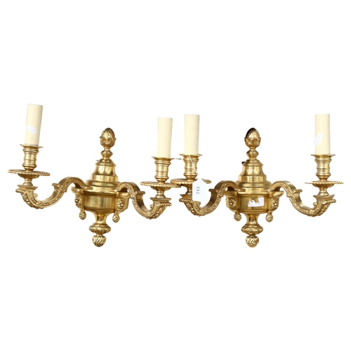 713 - A pair of ornate gilt-brass twin-sconce wall lights, 36cm across