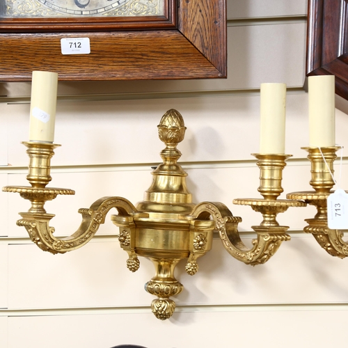 713 - A pair of ornate gilt-brass twin-sconce wall lights, 36cm across