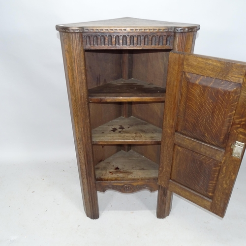 2302 - An oak corner cupboard with single panelled door with applied carved decoration. 63cm x 119cm x 40cm