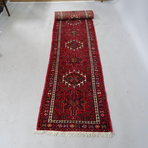 2323 - A red-ground Afghan design runner. 286cm x 63cm