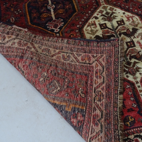 2329 - A red-ground Shiraz design rug. 170cm x 152cm