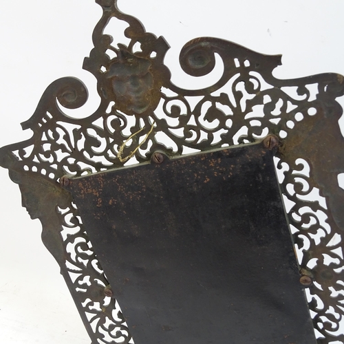 98 - A pierced and engraved cast-metal bevel-edge wall mirror, with single sconce and decorated with drag... 