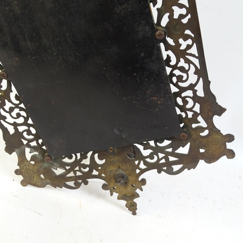 98 - A pierced and engraved cast-metal bevel-edge wall mirror, with single sconce and decorated with drag... 