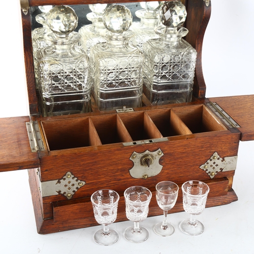 35 - An Edwardian 3 decanter oak tantalus, Gothic metal mounts, with glass cabinet, cribbage board drawer... 