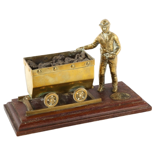 87 - A cast-brass coal mining figure and carriage on wood plinth, length 23cm