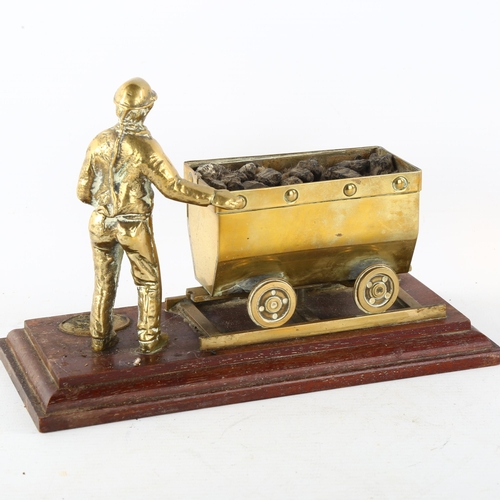 87 - A cast-brass coal mining figure and carriage on wood plinth, length 23cm