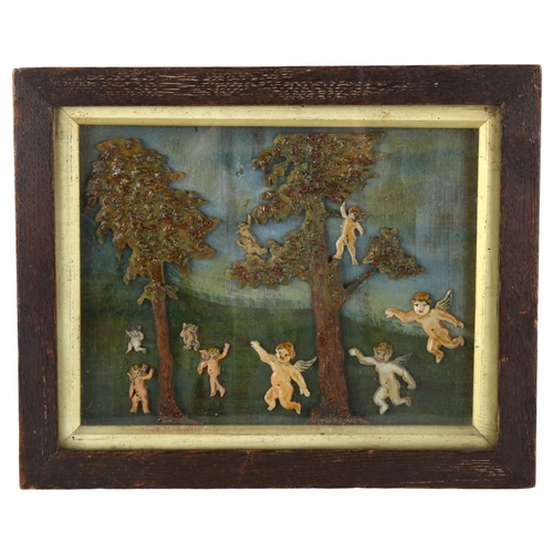 96 - A carved and painted wood/wax relief picture, depicting trees and cherubs in glazed frame, 21cm x 25... 