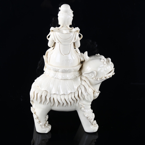 98 - A Chinese blanc de chine porcelain figure of Buddha riding a Dog of Fo, impressed seal marks on reve... 