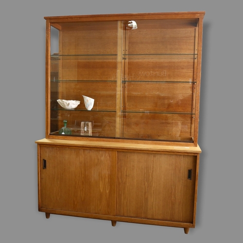 169 - A mid-century oak library display / bookcase, with glass shelving and sides to top, and cupboard und... 