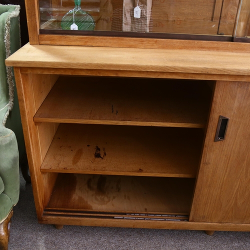 169 - A mid-century oak library display / bookcase, with glass shelving and sides to top, and cupboard und... 