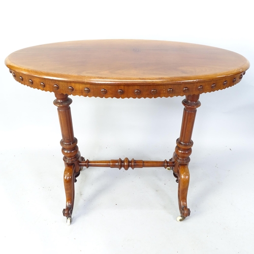 2090 - A Victorian Mahogany oval cantre table with fluted columns and turned stretcher, 94cm x 76cm x 57cm