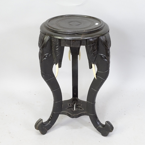 2122 - An ebonised circular topped occasional table on elephant carved supports. 35cm x 65cm