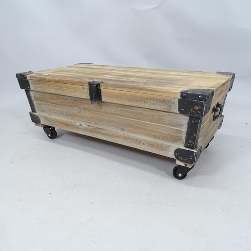 2128 - A contemporary pine storage box / low coffee table with lifting lid, raised on casters. 83cm x 33cm ... 