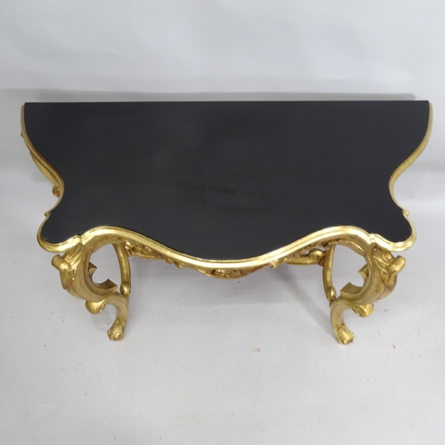 2141 - A gilt painted serpentine console table with black lacquered top. 130cm x 74cm x 57cm