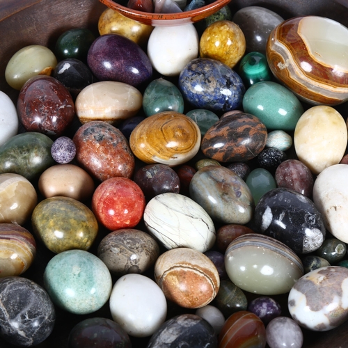 266 - A large quantity of ornamental eggs and various stones, in a hardwood bowl, bowl diameter 49cm.