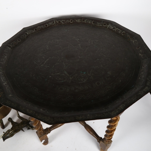 342 - An Eastern engraved brass tea tray on folding barley twist oak stand, 19th century brass saucepan on... 