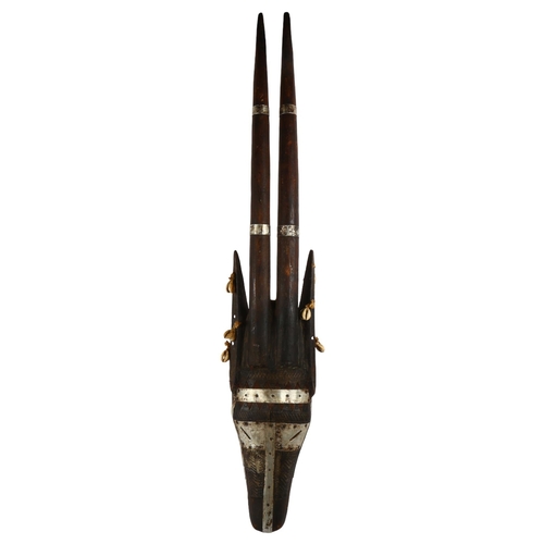 85 - An African hardwood mask, with pressed metal and shell decoration, L90cm