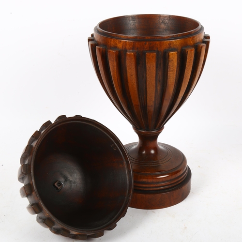 360 - A carved mahogany urn and cover, with fluted design and brass finial, 36cm