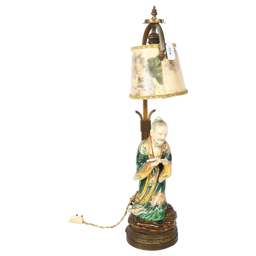 374 - A Japanese 19th century porcelain figure of a man holding a book, mounted on a gilt-metal lamp stand... 