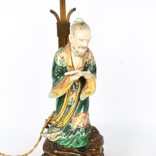 374 - A Japanese 19th century porcelain figure of a man holding a book, mounted on a gilt-metal lamp stand... 