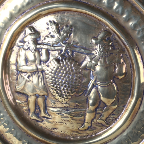 177 - An 18th century brass harvest bowl, relief embossed central panel depicting men carrying a grapevine... 