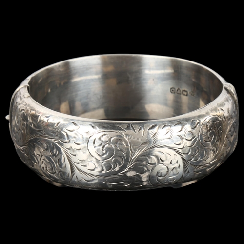 1295 - A mid-20th century silver hinged bangle, allover engraved foliate decoration, maker's marks S and E,... 