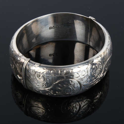 1295 - A mid-20th century silver hinged bangle, allover engraved foliate decoration, maker's marks S and E,... 